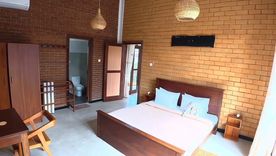 Bedroom with brick walls and a wooden bed — Syndeo Garden, Hikkaduwa