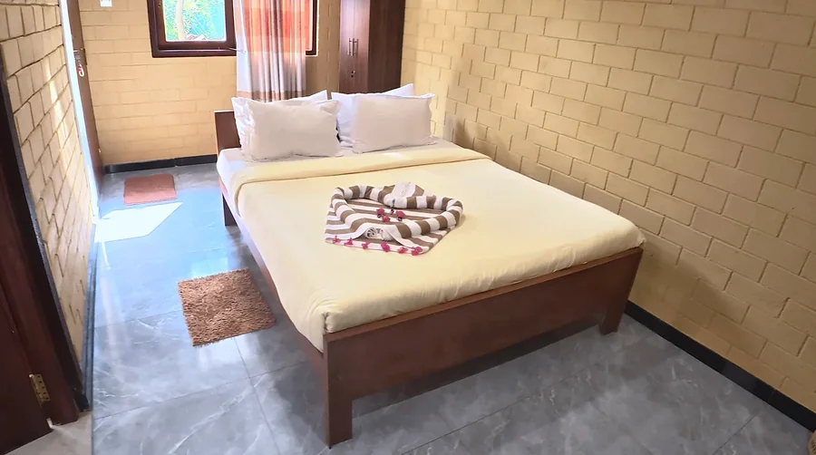 Bedroom with yellow brick walls and a wooden bed — Syndeo Garden, Hikkaduwa