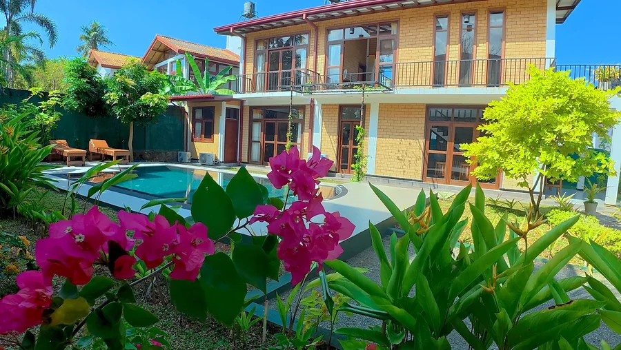 Tropical flowers with the villa and pool beyond — Syndeo Garden, Hikkaduwa